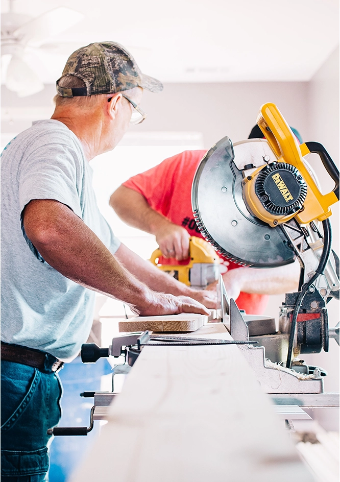 Two men working on a table with power tools.