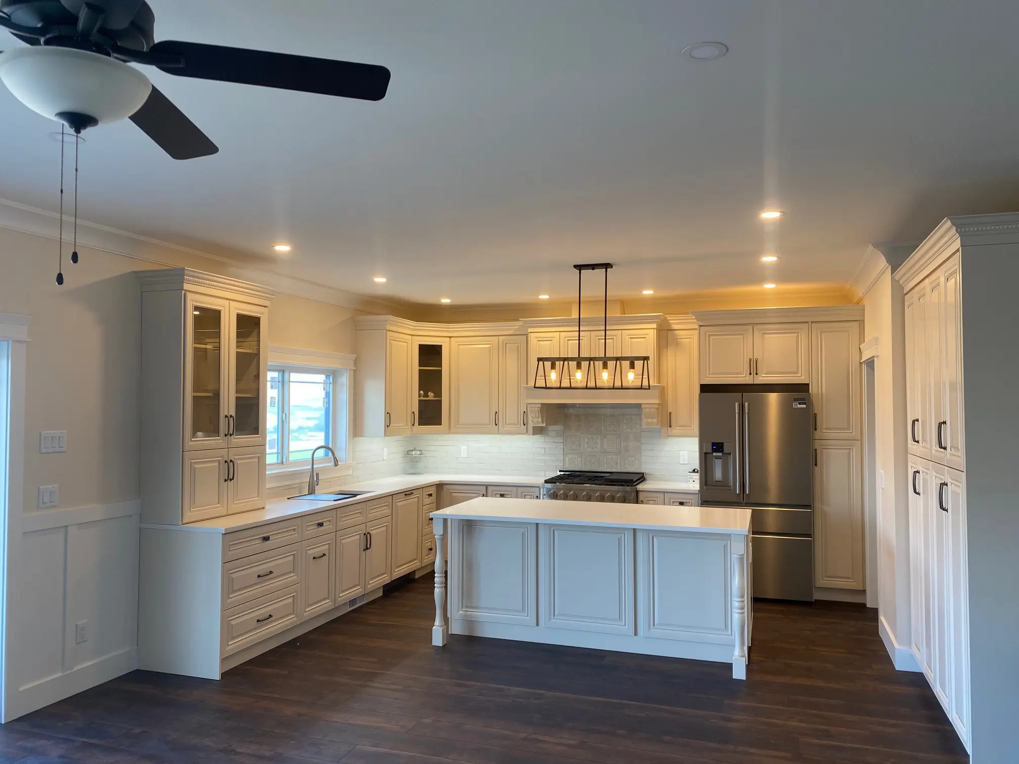 A kitchen with white cabinets and wooden floors.