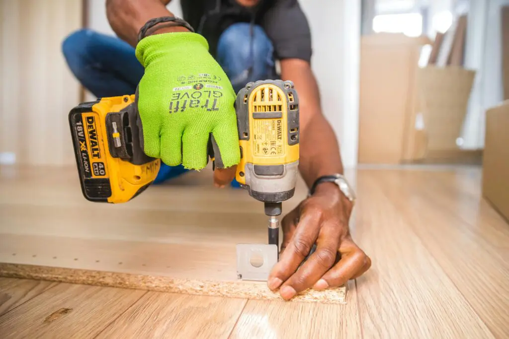 A person using a drill to install the floor.